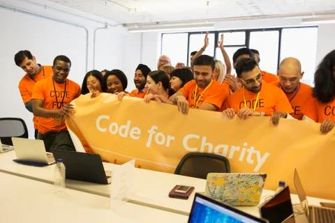 Hackers with banner coding for charity at hackathon Stock Photos