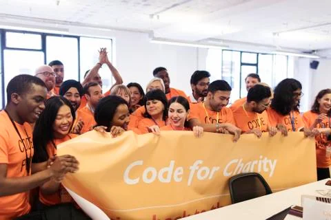 Hackers with banner coding for charity at hackathon Stock Photos