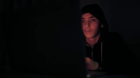 Hacker's hacking into the computer network. A young guy in a dark room typing Stock Footage 106021831