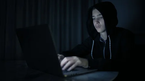 Hacker's hacking into the computer network. A young guy in a dark room typing Stock Footage 106022004