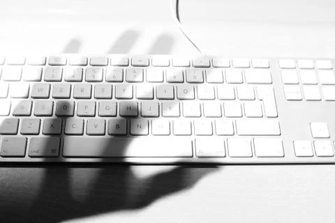 Hackers hand hovering over a computer keyboard Stock Photos