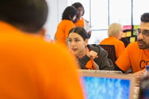 Hackers at laptops coding for charity at hackathon Foto stock