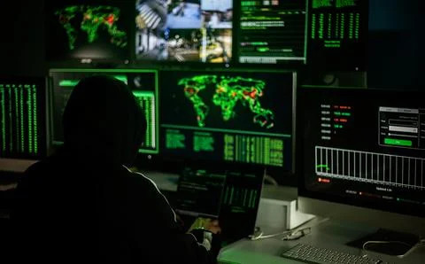 Hackers working on computers showing world maps and security camera footage 写真素材