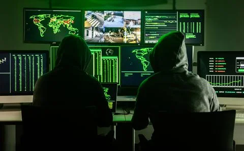 Hackers working on computers showing world maps and security camera footage Foto stock