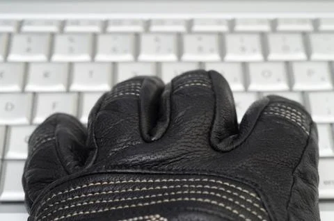 Hacking concept with hand in black leather glove over the laptop keyboard Stock Photos