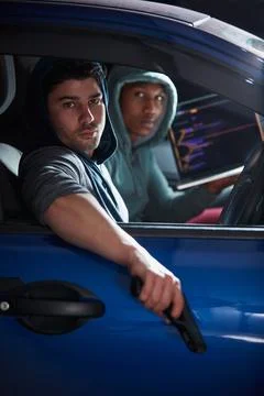 Hacking is a crime. two armed young hackers using a laptop in a car. Stock Photos