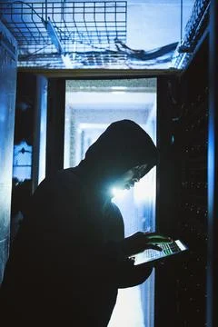 Hacking into your mainframe. a hacker using a digital tablet in a server room. Stock Photos