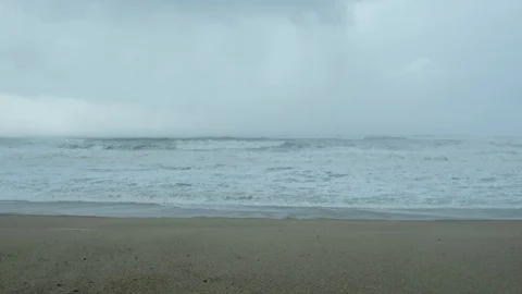 Hailstones fall on cold beach in winter with dark, grey, moody, stormy sky Stock Footage 119801326