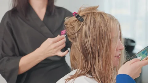 Hair coloring session, Client seated as expert stylist performs hair dye Stock Footage 327487929