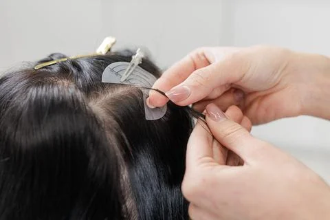 Hair extensions installation close up with micro bead method at crown in salo Stock Photos