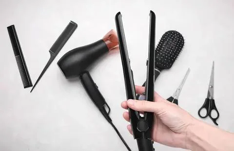 Hair styling tools including flat iron and brush on white background Stock Photos