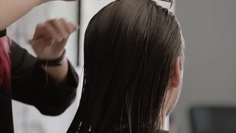 Hair stylist combing a man's long hair in a modern salon Stock Footage 272741453