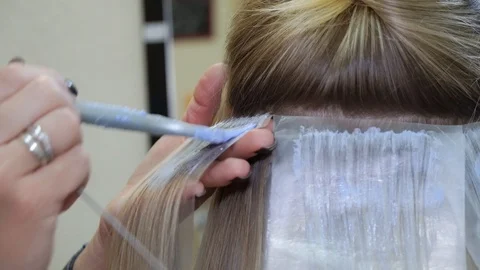 Hair stylist dye hair in hair salon.divides hair into strands and paints it. Stock Footage