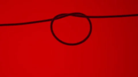 Hair that is tied into a round loop on a red background. Macro shot of a thin Stock Footage 232468339
