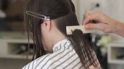 Hairdresser-stylist is cutting hair of a girl client Stock Footage