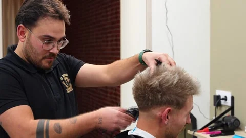 Hairdresser talking with next client while cutting hair Stock Footage 320458322