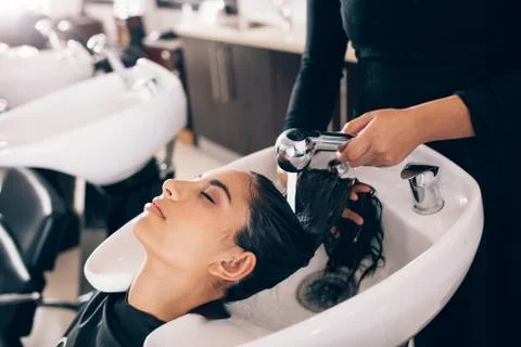 Hairdresser washing hair of customer at salon Stock Photos