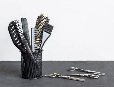 Hairdressing combs scissors in stand on gray white background. Hair salon Stock Photos