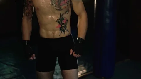 Hairless with pigtail and tattoos, free fighter training punching bag. 4K Stock Footage