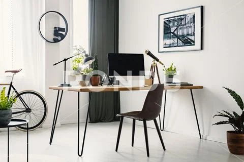 Hairpin desk with mockup monitor, plants and telescope standing in bright roo Stock Photos
