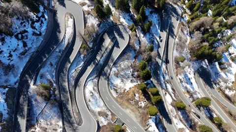 Hairpin loops stack down forested mountainside bus truck cars navigate Stock Footage 345961917