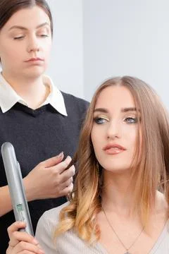 A hairstyle master makes styling for a young girl model Stock Photos