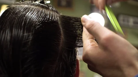 Hairstyling process. Close-up of a barber cutting hair of a young bearded man Stock Footage 69960441