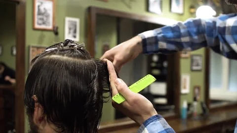 Hairstyling process. Close-up of a barber cutting hair of a young bearded man Stock Footage 69960604