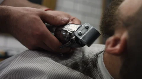 Hairstyling process. Close-up of a barber drying hair of a young bearded man Stock Footage 68062170