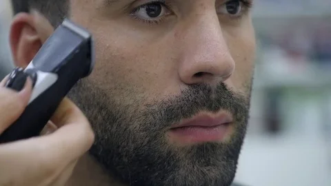 Hairstyling process. Close-up of a barber drying hair of a young bearded man Stock Footage 81553399