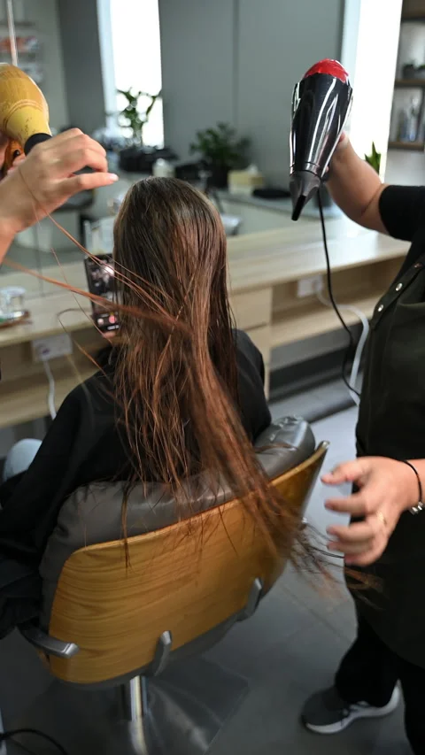Hairstylists using blow dryers simultaneously on long wet brown hair. Haird.. Vídeo Stock 340227356