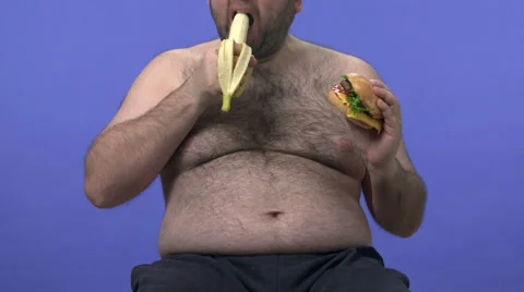 Hairy overweight man choosing between banana and hamburger. He chooses banana. Stock Footage 45926547