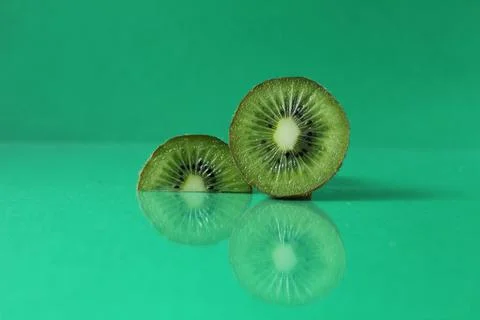 Half and a circle of kiwi kusrchek with reflection on a green background with Stock Photos