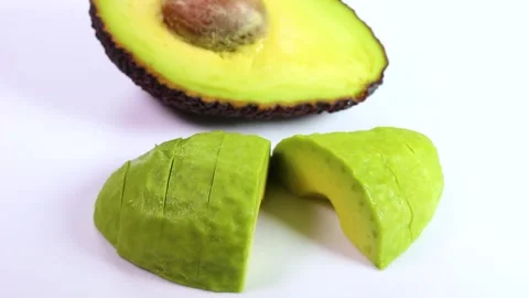 Half and sliced ​​avocado on white background, rotating Stock Footage 319412863