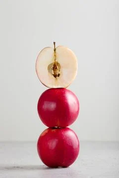 Half apple balanced on top of red apple Stack on white background Stock Photos