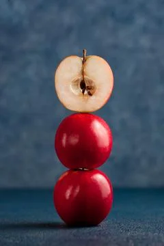Half apple balanced on top of red apple stack on blue background Stock Photos