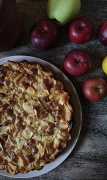 Half an Apple pie on a light round plate. Red, yellow, green apples around th Stock Photos