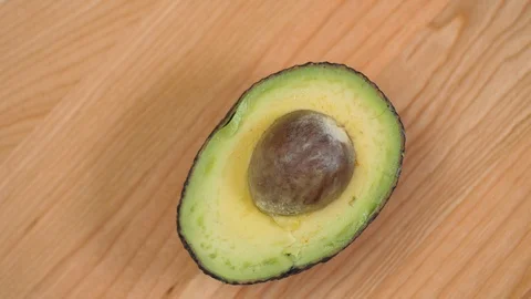 Half an Avocado with nut spinnin on cutting board 03 스톡 동영상 110886923