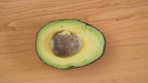 Half an Avocado with nut spinnin on cutting board 01 Video stock 110886971