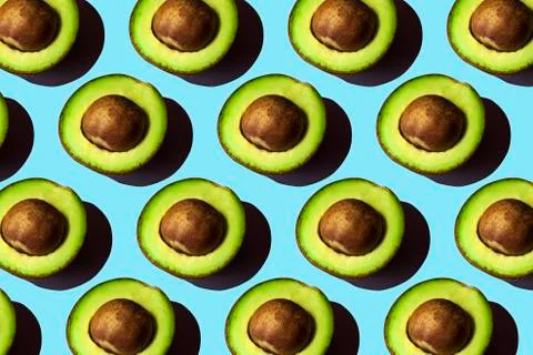 Half avocado, pattern on blue backdrop. keto diet food photo. Fresh fruit. Foto stock