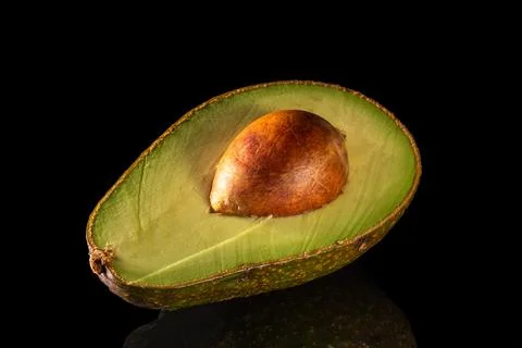 Half of avocado with pit on black background, close-up, detailed photo Stock Photos