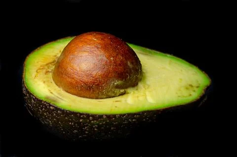Half an avocado with the pit Stock Photos