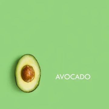 Half avocado with seed on a green background in a top view Stock Photos