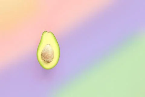 A half of avocado with seed on multicolored background. Top view. Stock Photos