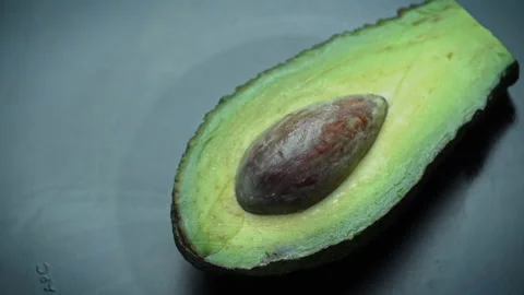 Half of an Avocado with a Stone Rotates in a Circle on a Black Background Stock Footage 173091987