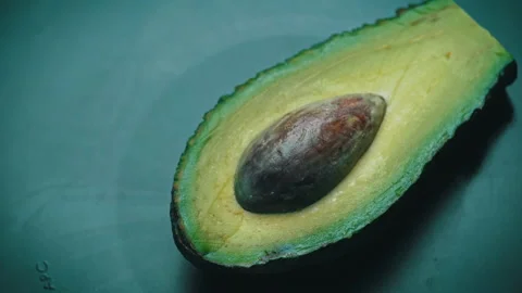 Half of an Avocado with a Stone Rotates in a Circle on a Black Background Stock Footage 174415596