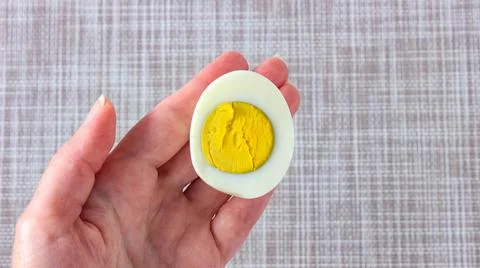 Half of a boiled egg in your hand. A quick snack. Stock Photos