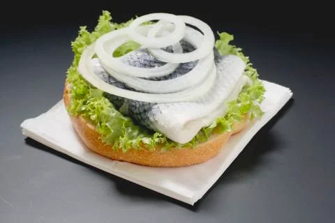 Half bread roll topped with herring &amp; onions on paper napkin Stock Photos
