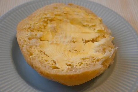 Half buttered bread roll on a plate Stock Photos
