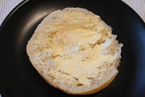 Half buttered bread roll on a plate 스톡 사진